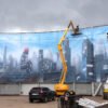 Bâche très grand format micro perforée sur structure en tubes pour un parc d'attraction Walygator, impression couleur haute définition illustrant une ville avec building.