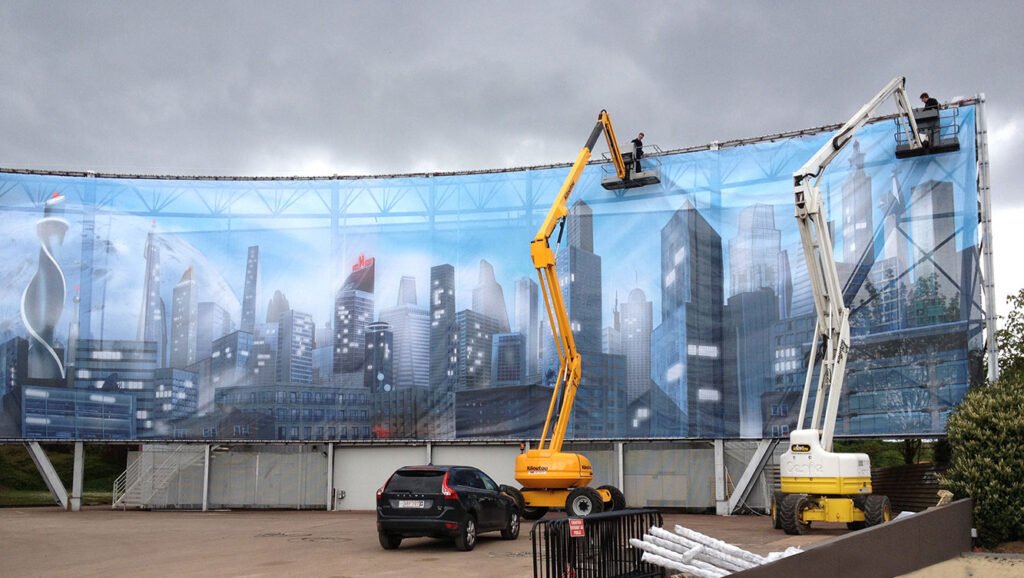 Bâche très grand format XXL micro perforée sur structure en tubes pour un parc d'attraction Walygator, impression couleur haute définition illustrant une ville avec building.
