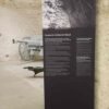 Impression vinyle autocollant repositionnable - Affiche promotionnelle grand format - Pose facile sans bulles Panneau d'information vertical en vinyle imprimé avec texte bilingue et photo, installé dans un espace au Musée de Pompelle à Metz près d'une pièce d'artillerie.