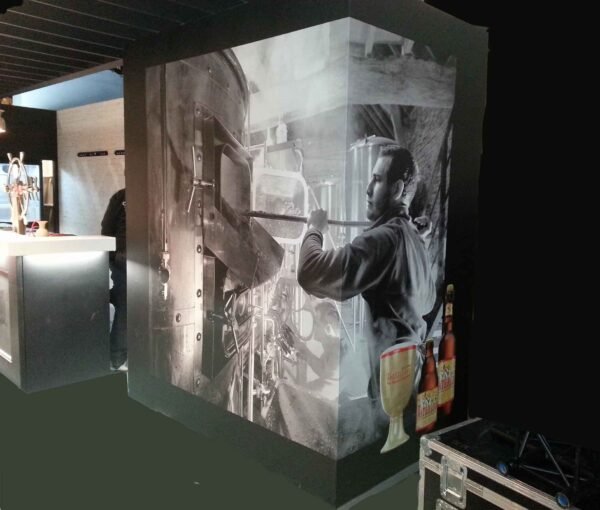 Structure modulaire cubique recouverte d’une toile murale imprimée en une seule pièce, montrant un brasseur en action, dans un espace d’exposition pour Martin's.