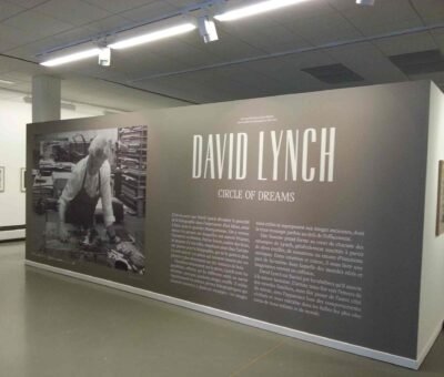 Toile murale d’exposition – Sans joint, impression continue Mur d’exposition imprimé en grand format sur toile murale sans joint, présentant une photo de David Lynch et du texte explicatif, au Musée de la photographie.