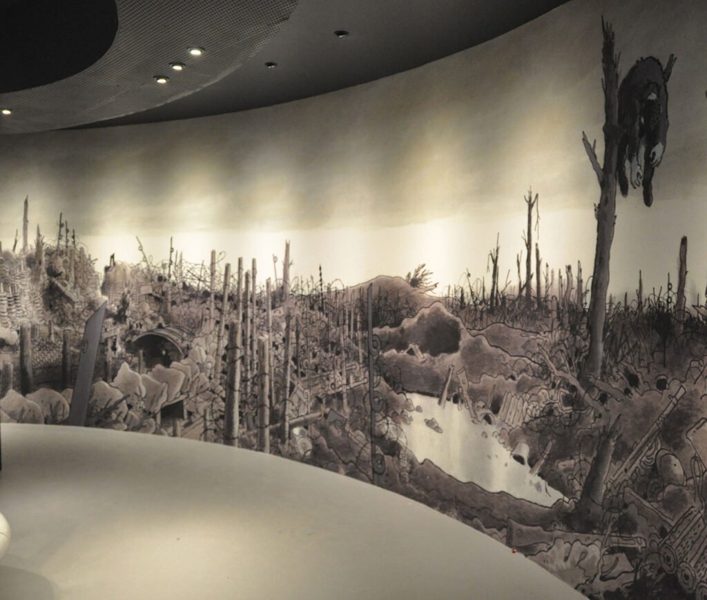 Fresque murale panoramique imprimée en une seule pièce, représentant un champ de bataille, installée sur un mur courbe dans un espace d’exposition.