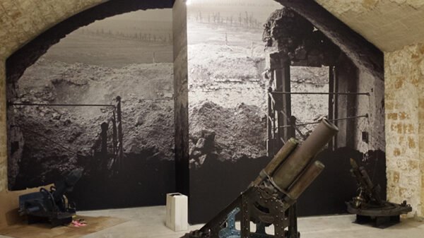Mur d’exposition imprimé en grand format sur toile murale sans joint, représentant des tranchées de guerre, dans un espace muséal.