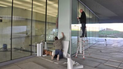 Pose de vinyle sur vitrine en verre par deux techniciens professionnels