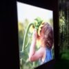 Impression grand format sur tissu rétroéclairé d'une petite fille tenant un tournesol géant, installée dans un cadre extérieur verdoyant.