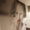Toile murale en une seule pièce imprimée en grand format, représentant une jeune fille mangeant une fraise, installée dans un espace intérieur moderne pour Batibouw