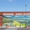 Fresque murale panoramique imprimée sur panneaux de stratifié HPL et installée sur la façade d’un aérodrome.