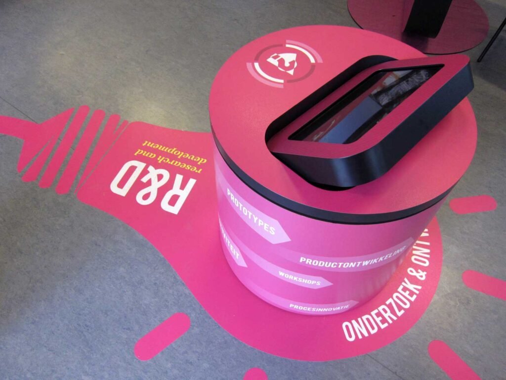 Vinyle de sol imprimé en forme d’ampoule sous un présentoir, graphique rose pour communication au sol.